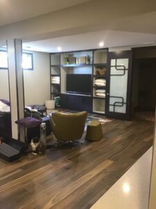 Finished basement family room with hardwood floor and built-in media wall