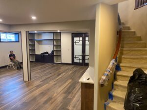 Finished basement with built-in shelving, hardwood floor and open staircase